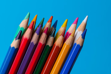 Set of wooden colored pencils on a blue sheet of paper background