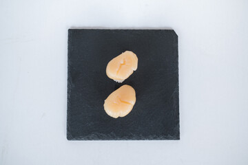 Two Nigiri Sushi with scallop served on black tray. Two sushi pieces served on black slate isolated on white background. Japanese food.