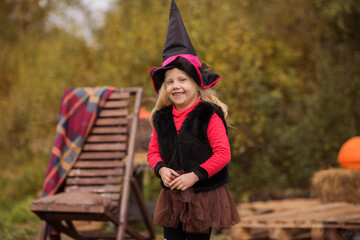 Little girl with blond hair in a witch hat smiles happily