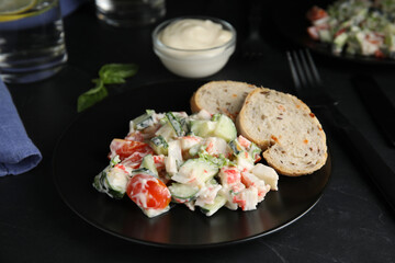 Delicious salad with mayonnaise on black table