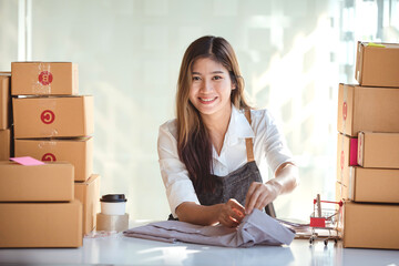 Small start-up business owners using computers at work, freelancers, saleswoman, checking production orders. Pack products for delivery to customers