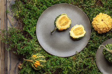 Decorative small pumpkins on grey stoneware plates  on green fresh thyme background