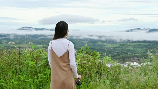 Asian woman with retro camera taking photo of landscape nature on mountain in tropical rainforest