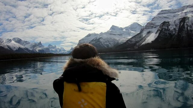 Man traveler rowing a canoe into the Spirit Island with Canadian Rockies on Maligne lake at Jasper national park