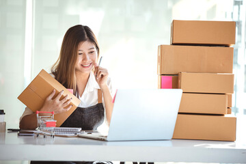 Small start-up business owners using computers at work, freelancers, saleswoman, checking production orders. Pack products for delivery to customers