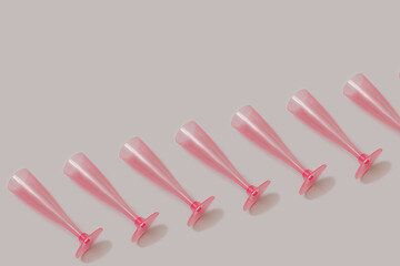 Trendy seamless pattern made with many pink holiday wine glass on a pastel gray and purple background. Christmas, holiday and party backdrop.