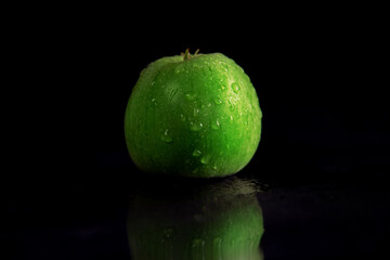 fresh juicy green apple, in drops of dew on a black background