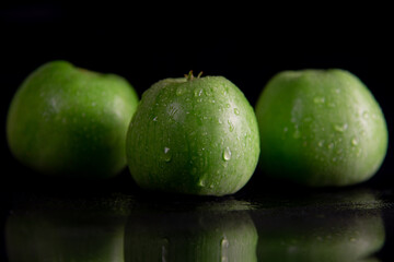 fresh juicy green apples, in drops of dew on a black background