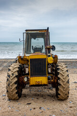 Old yellow tractor on a beach
