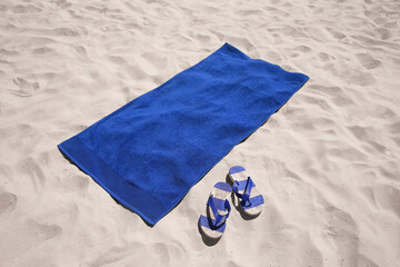 Flip flops and blue beach towel on sand - Powered by Adobe