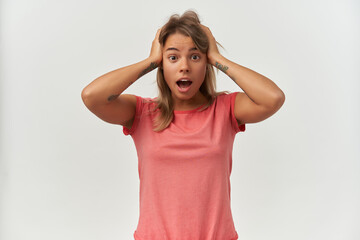 Indoor shot of young adult female, shouting and touching her head with negative facial expression. Isolated over white background