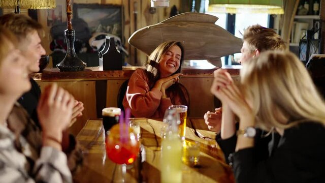 Group of happy multiethnic friends having fun together, drinking bottled beer in a bar or at home, celebrating, happily smiling - friendship, togetherness concept