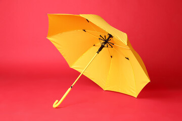Stylish open yellow umbrella on red background