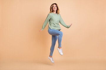Fototapeta na wymiar Full length body size photo woman jumping up in casual clothes isolated pastel beige color background