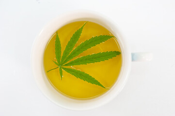 Tea in a glass that is extracted from cannabis on a white background.