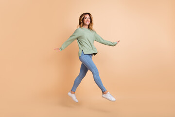 Fototapeta na wymiar Full length body size view of attractive cheerful woman jumping good mood isolated over beige pastel color background