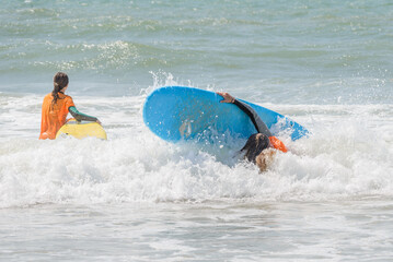 surf student falls off her board during her first surf lesson.