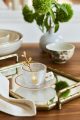 Creative and elegant dining room composition with classy porcelain, golden tray and beautiful personal accessories. Luxury apartments. Beauty in the details. Template.