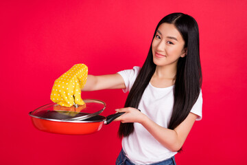 Photo of cheerful positive korean lady hold pan look camera wear glove white t-shirt isolated red color background