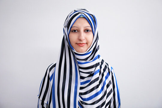 Portrait of a young Muslim woman wearing hijab (head scarf) on white background
