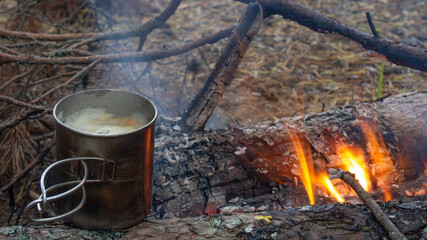 cooking hiking food on a campfire in a metal mug