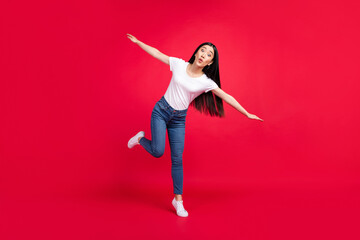 Full length photo of young excited asian girl pouted lips hands wings plane fly isolated over red...