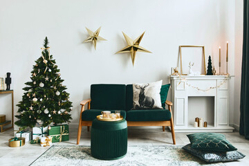 Stylish christmas living room interior with green sofa, white chimney, christmas tree and wreath,...