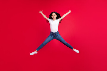Full length photo of young excited asian girl happy positive smile jump star energetic isolated over red color background