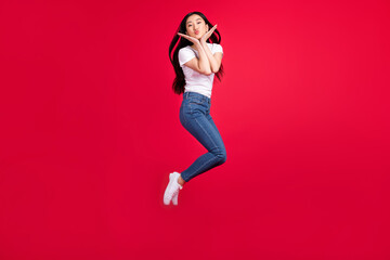 Fototapeta na wymiar Photo of romantic affectionate lady jump blow air kiss wear white t-shirt jeans footwear isolated red color background