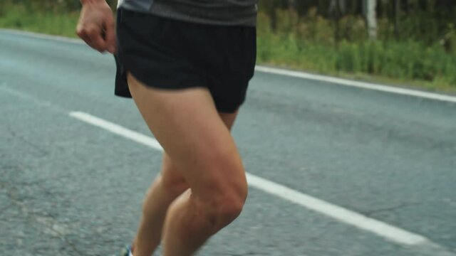 Tilt up shot of Caucasian female athlete in sportswear running on road while training for triathlon race on summer day