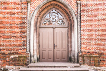 Old grungy red brick wall with big wooden door.