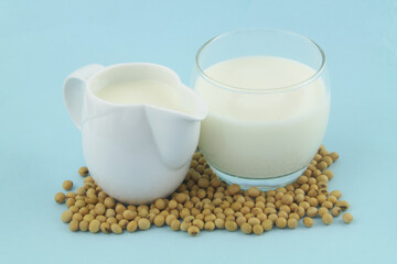 Soy milk with soy beans on blue background close up