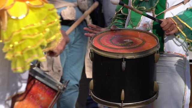 A group of drummers playing rhythmic music during the parade at the carnival. Dressed in colorful traditional costumes.