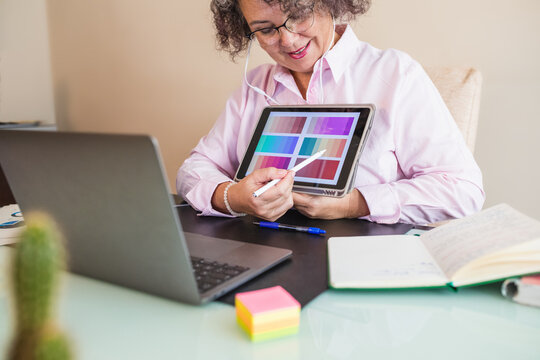 Crop businesswoman showing color palette on tablet during video call