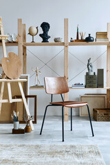 Unique artist workspace interior with stylish desk, wooden easel, bookcase, artworks, painting accessories, decoration and elegant personal stuff. Modern work room for artist. Template.