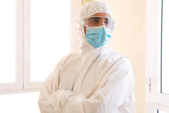 Confident doctor with crossed arms in PPE suit at work
