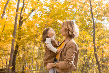 Fototapeta premium Young mother with her little daughter in an autumn park. Fall season, parenting and children concept.