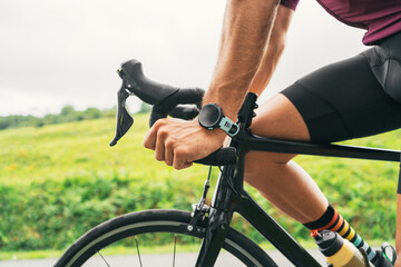 Crop cyclist in smart watch riding bicycle on road