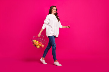 Obraz na płótnie Canvas Full size profile side photo of young girl happy positive smile go supermarket buy fresh food fruit isolated over pink color background