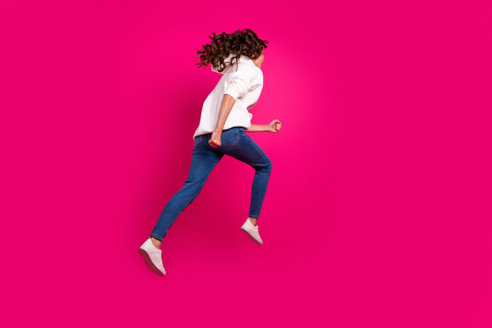 Rear back view photo of sportive lady jump run fast hurry wear white hoodie jeans shoes isolated pink color background