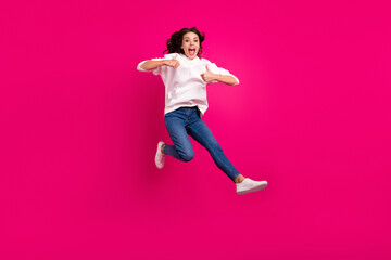 Full length photo of young girl happy positive smile jump up show thumbs-up like cool ad isolated over pink color background
