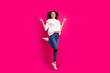 Photo of inspired active lady jump show v-sign wear white hoodie jeans footwear isolated pink color background