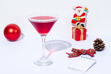 a red drinking glass a notebook with a pencil and Christmas decorations isolated on a white background