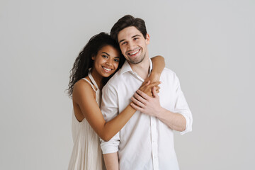 Young multiracial couple hugging and smiling at camera