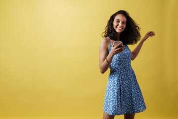 Young hispanic woman dancing while using mobile phone