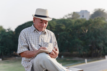 Asian old man sitting and relaxing in public park.