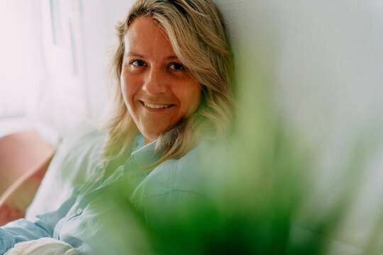Smiling woman resting on bed at home