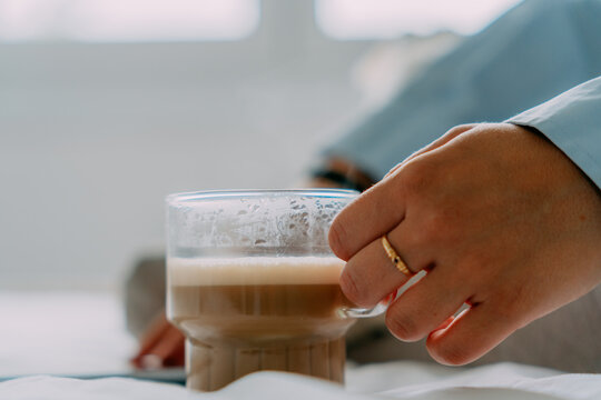 Crop woman with aromatic latte on bed