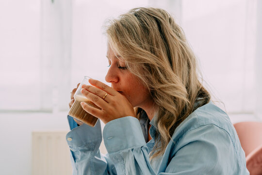 Dreamy woman enjoying delicious latte at home