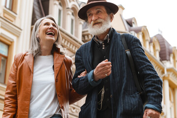 White senior couple talking and laughing while walking on street